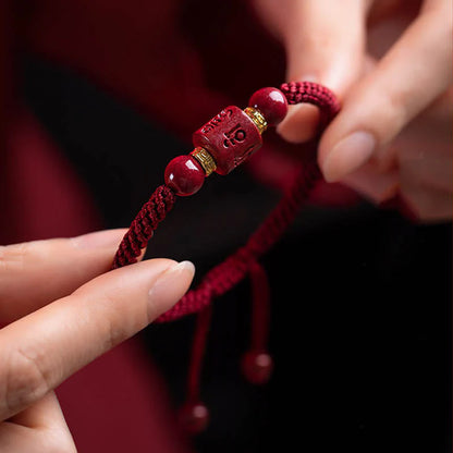 Tibetan Cinnabar Red String Bracelet held in hand, showcasing detailed engraving of Six True Words