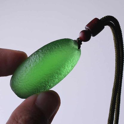 Green meteorite pendant necklace held in hand, emphasizing its cosmic energy and protective powers