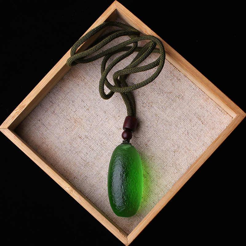 Green meteorite pendant necklace displayed on a surface, demonstrating its elegant and protective design