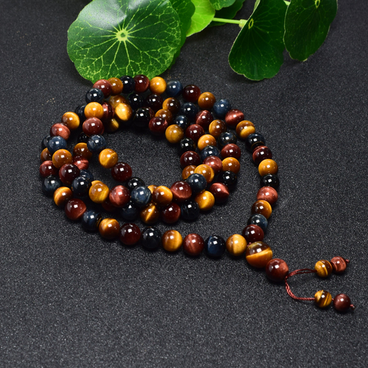 Close-up of Tibetan 108 Tiger's Eye Mala Beads on green leaves, highlighting spiritual energy