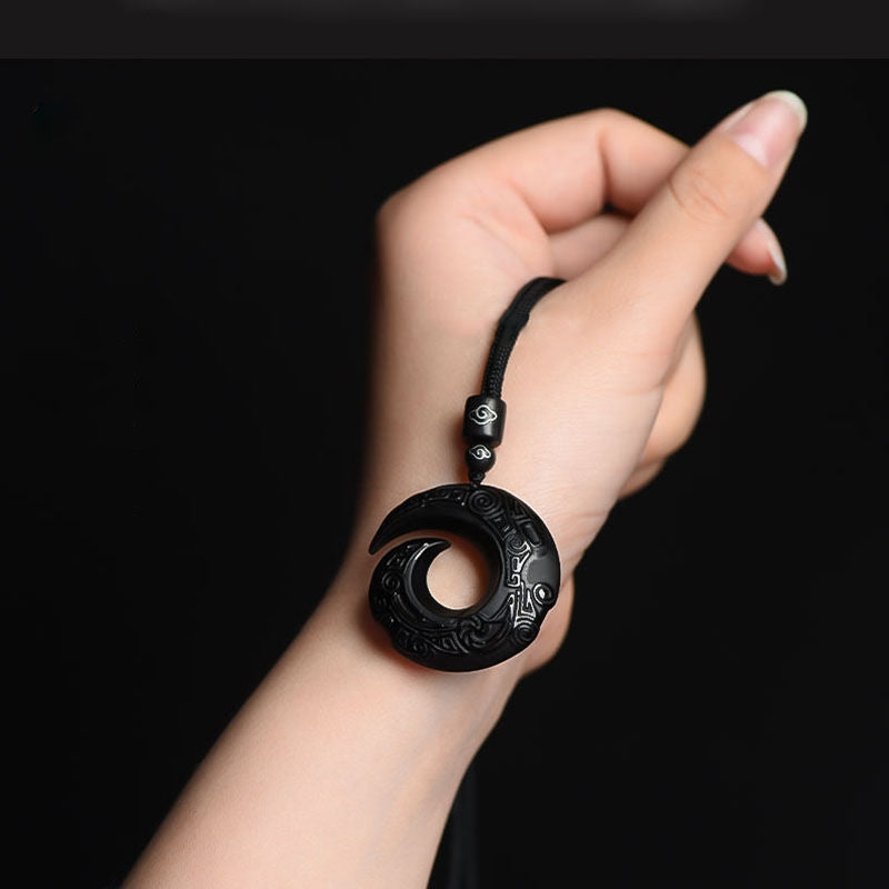 Obsidian pendant manifesting necklace displayed on hand, highlighting its detailed craftsmanship and good fortune symbol