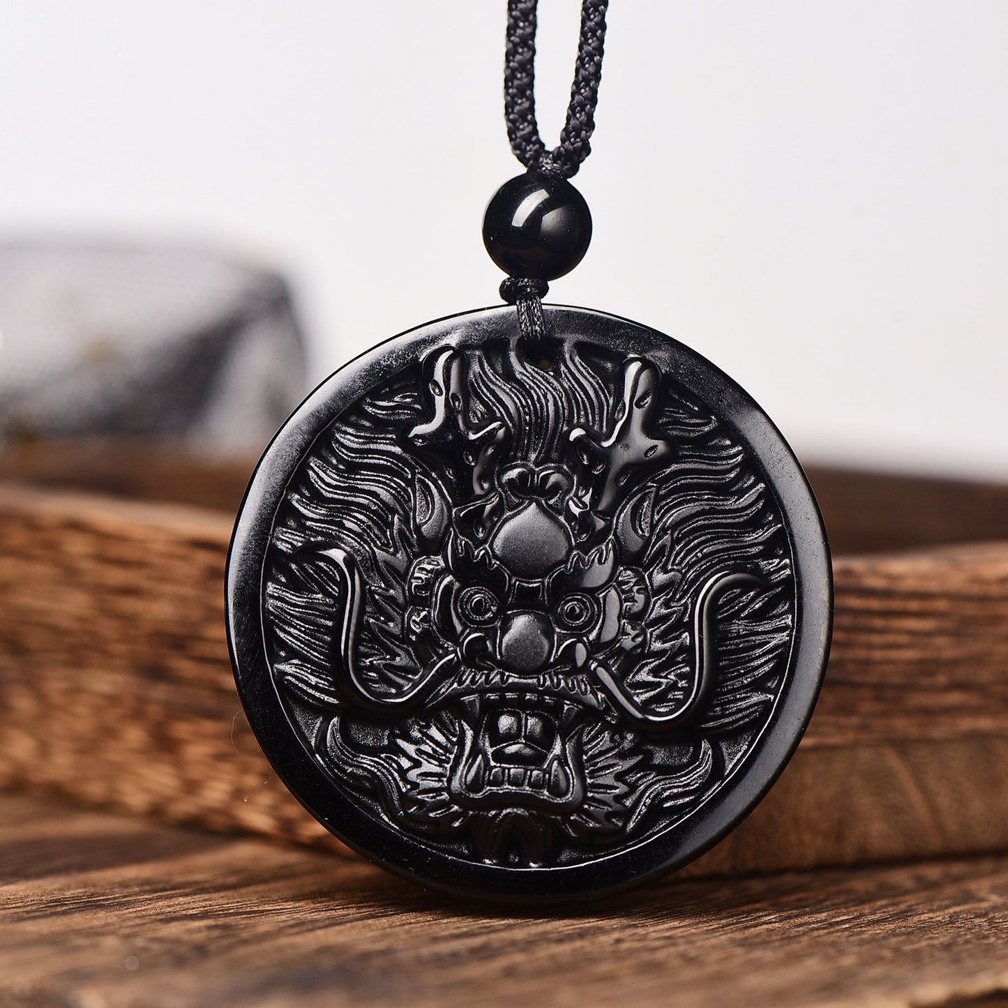 Close-up of carved dragon on obsidian pendant necklace, showcasing intricate design