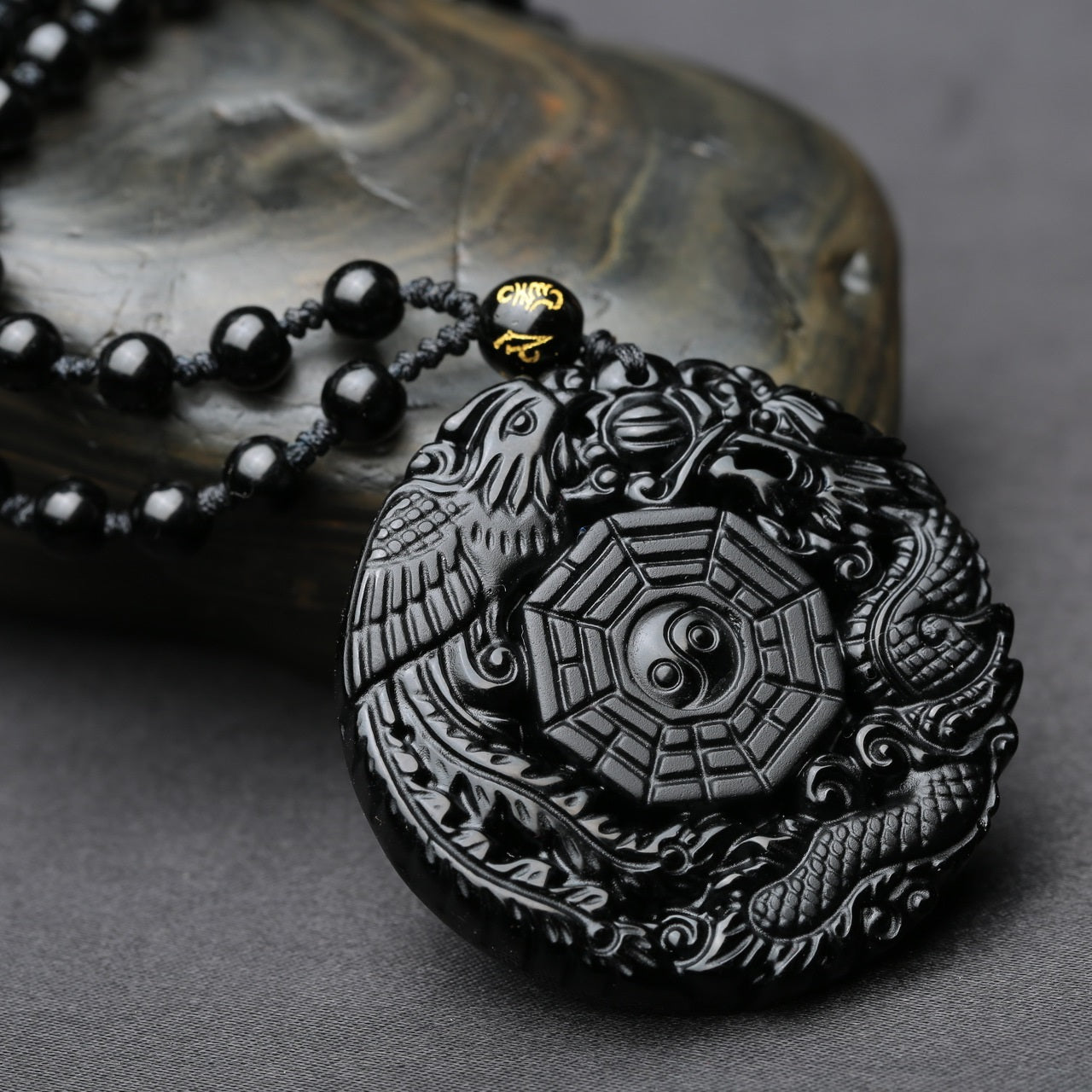 Side view of obsidian pendant necklace featuring dragon and phoenix with Taiji symbol