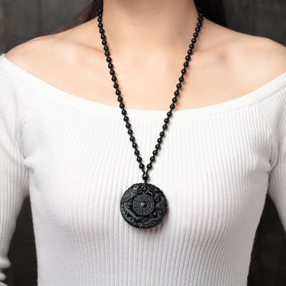 Obsidian pendant necklace worn by female model, highlighting the dragon and phoenix design