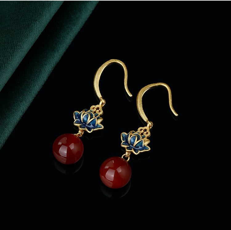 Display of pearl lotus flower earrings on a neutral background, highlighting the intricate design and vibrant jade accent