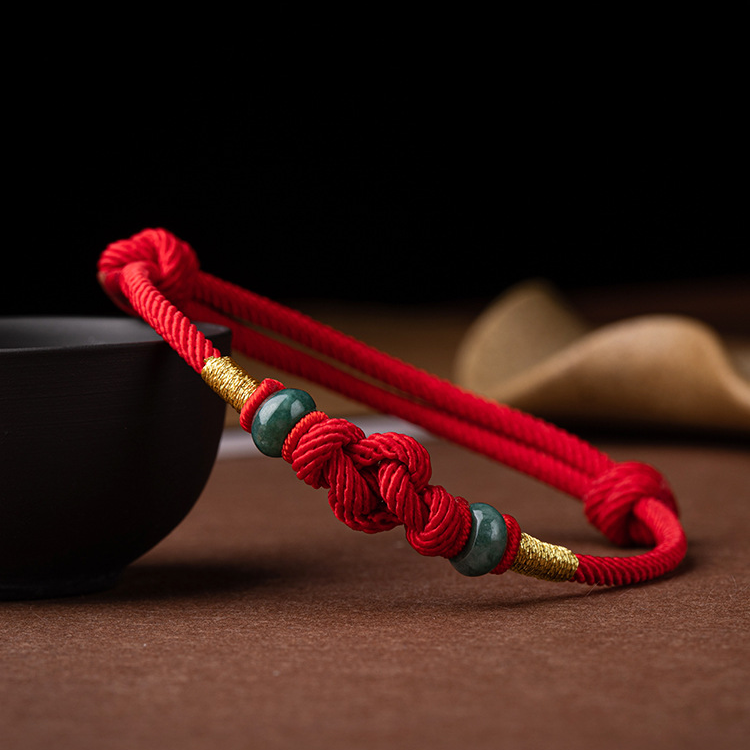 Detailed view of the red string jade lover's knot bracelet, highlighting the jade beads