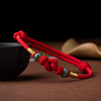 Detailed view of the red string jade lover's knot bracelet, highlighting the jade beads