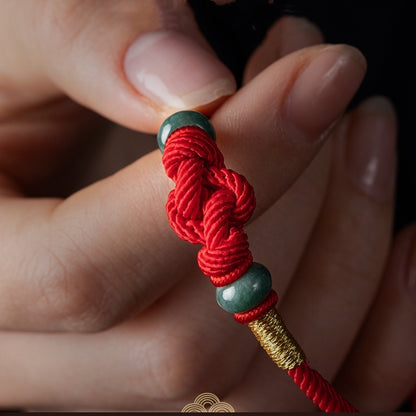 Red string jade bracelet on hand, featuring the lover's knot and jade beads