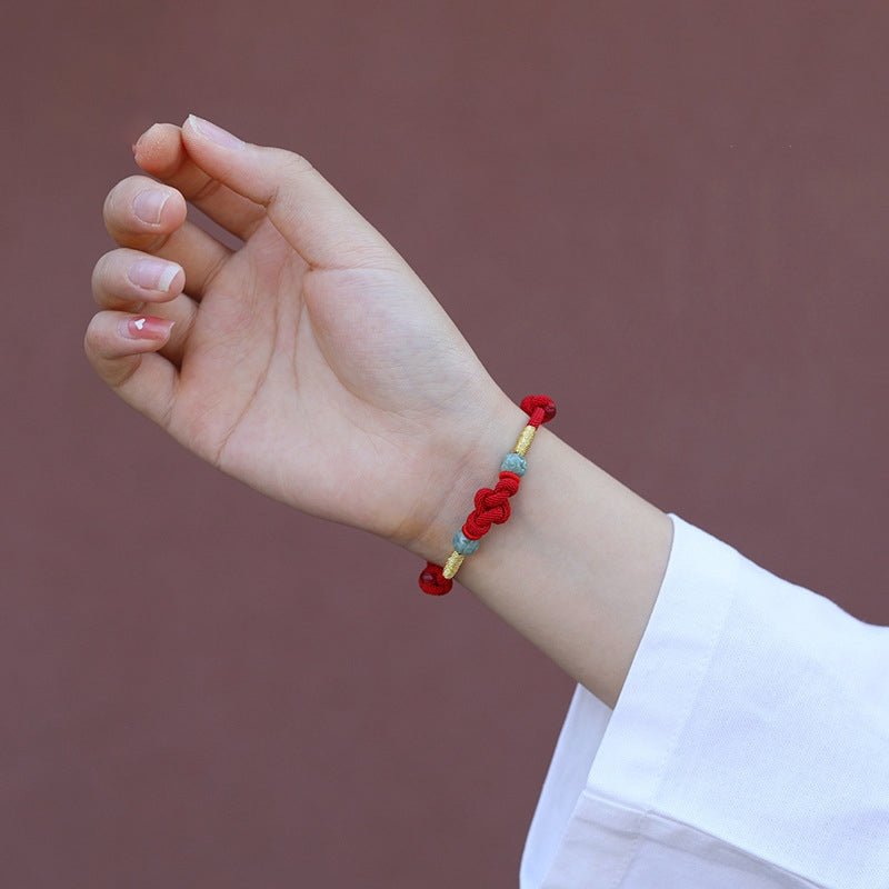 Red string jade lover's knot bracelet worn on the wrist