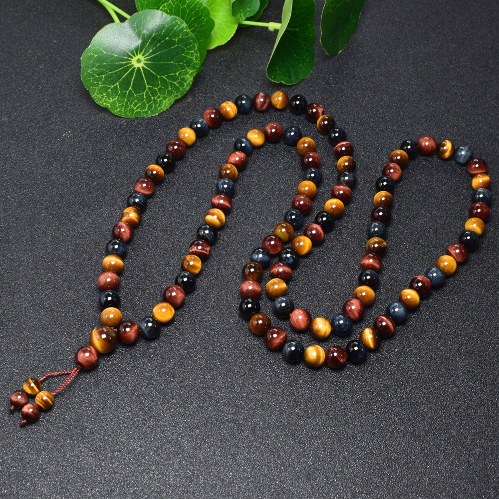 Tibetan Tiger's Eye Mala Beads on green leaves, representing healing and inner peace