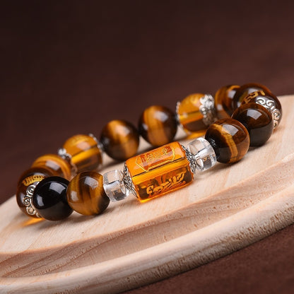 Detailed view of the carved Three-Faced God crystal charm on the Tiger's Eye bracelet