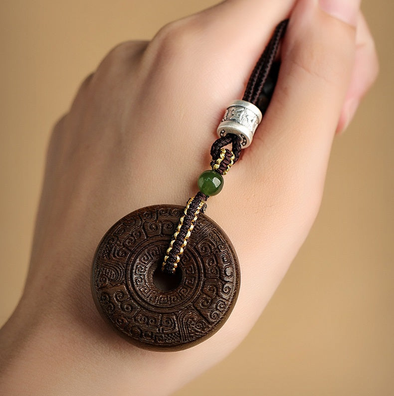 Close-up of wood pendant necklace with silver clasp and Hetian jade stone